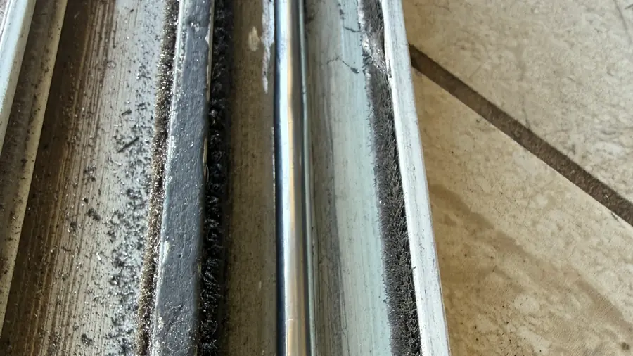 Dirty sliding door track close-up with debris along the rail