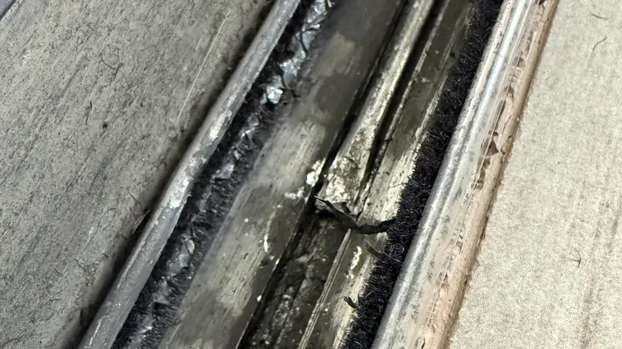 Close-up of a rough sliding door lower track