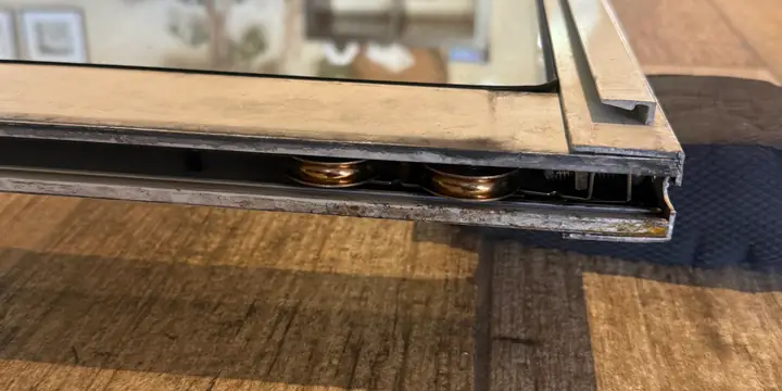 Sliding patio door panel and rollers near the lower edge